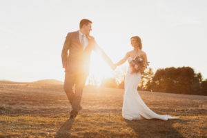 Bride and groom holding hands during sunset