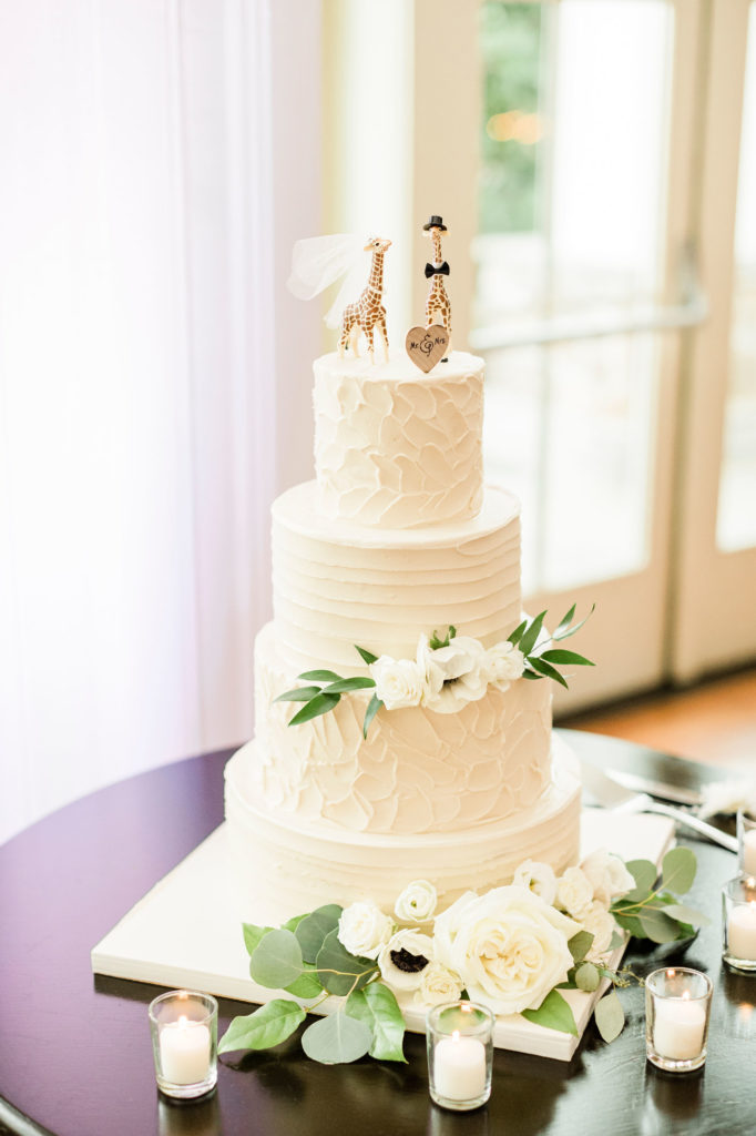 buttercream wedding cake with flower decorations and giraffe cake toppers